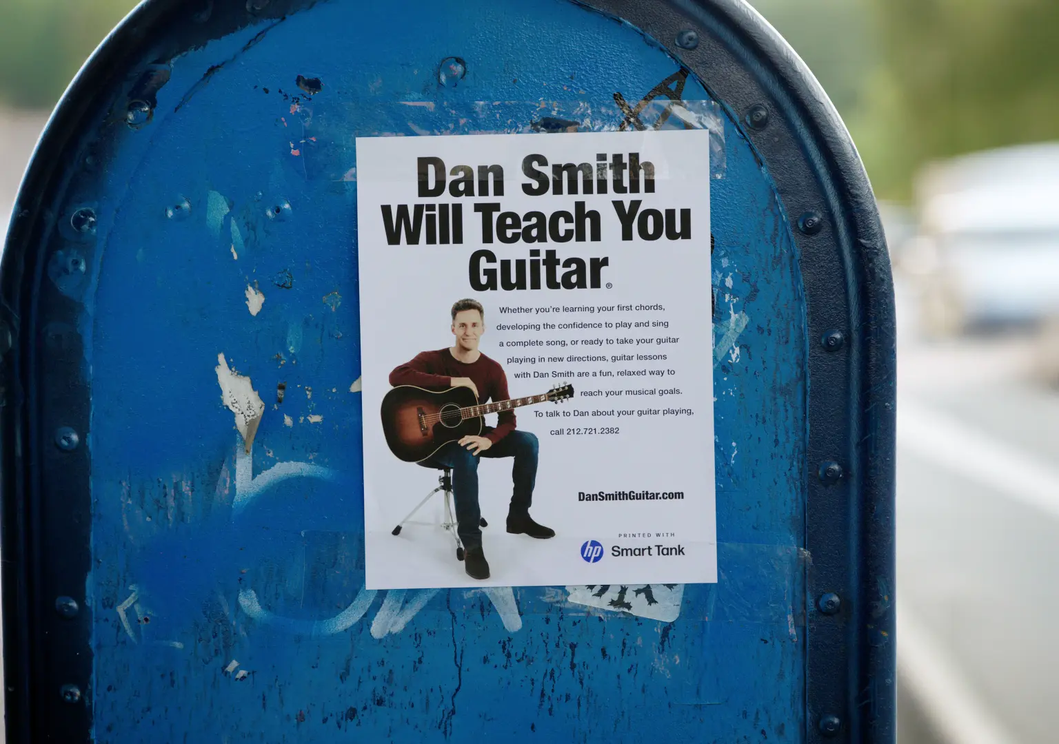 A “Dan Smith Will Teach You Guitar” flyer taped to a New York City mailbox