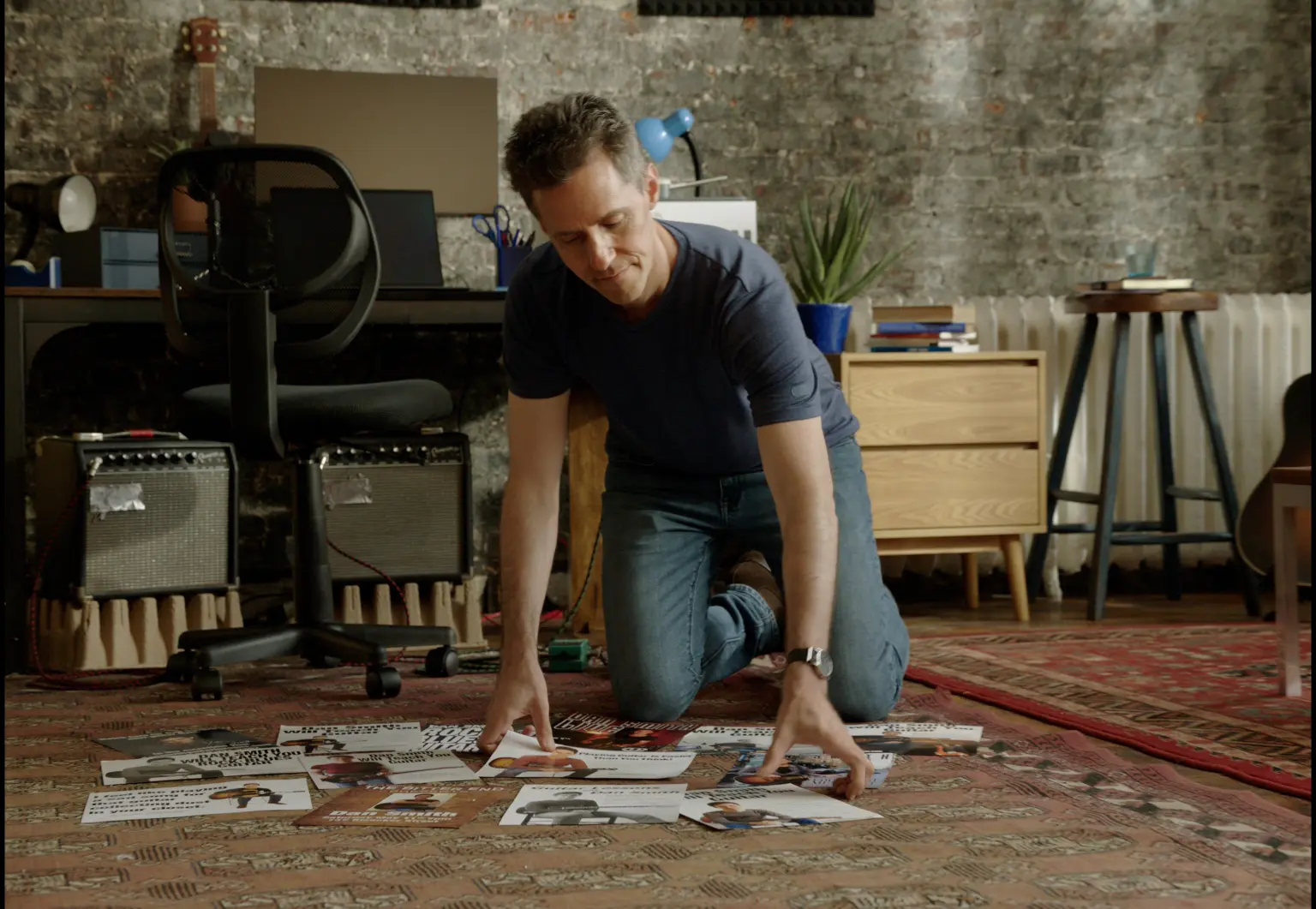 Dan Smith laying out guitar lesson flyers on the floor of his studio